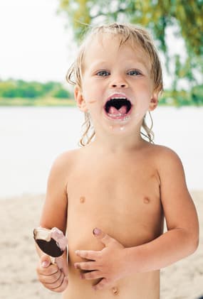 Enfant avec une glace vendu par un marchand ambulant sur une plage